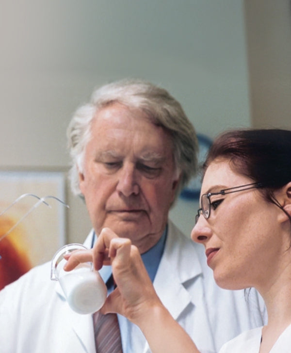 Dr Heinz Maurer and another scientist in a clinical setting inspecting a cosmetic cream.