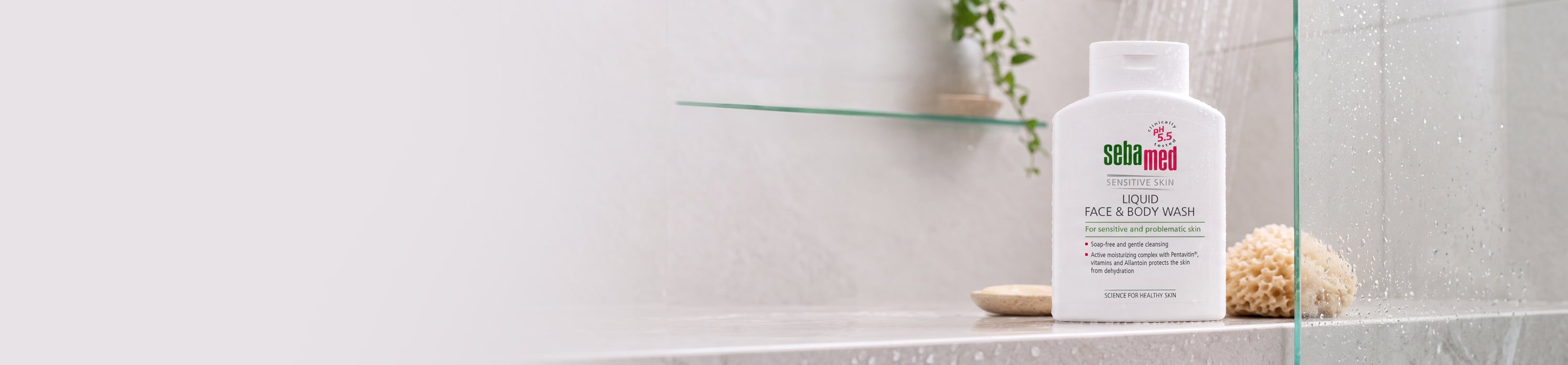 A white bottle of sebamed Liquid Face and Body Wash, displayed on a glass shelf in a bright, modern bathroom setting.