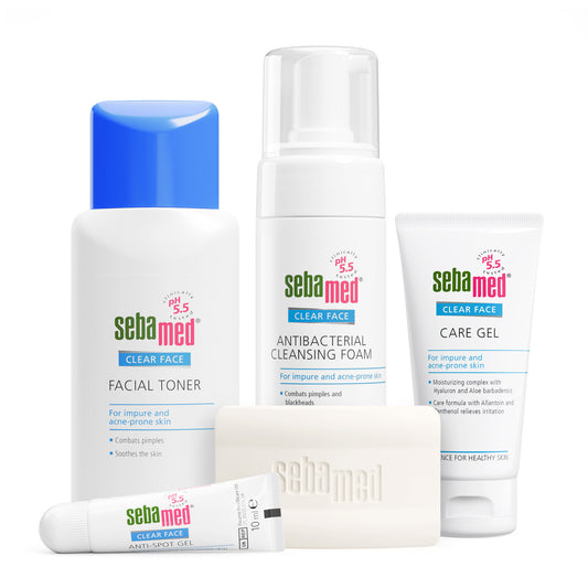 A Sebamed Clear Face skincare set on a white background, including a facial toner with a blue cap, a cleansing foam pump bottle, a care gel tube, a cleansing bar, and an anti-spot gel tube.