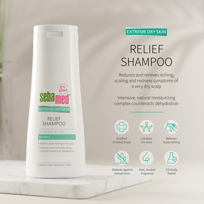 Sebamed Extreme Dry Skin Relief Shampoo shown in a white bottle on a marble pedestal with product text and benefit icons on a soft beige background.