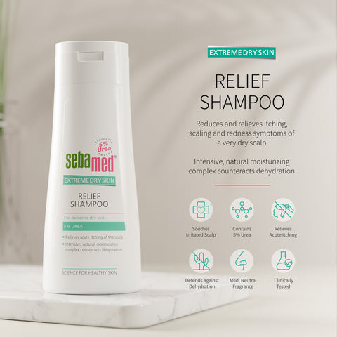 Sebamed Extreme Dry Skin Relief Shampoo shown in a white bottle on a marble pedestal with product text and benefit icons on a soft beige background.
