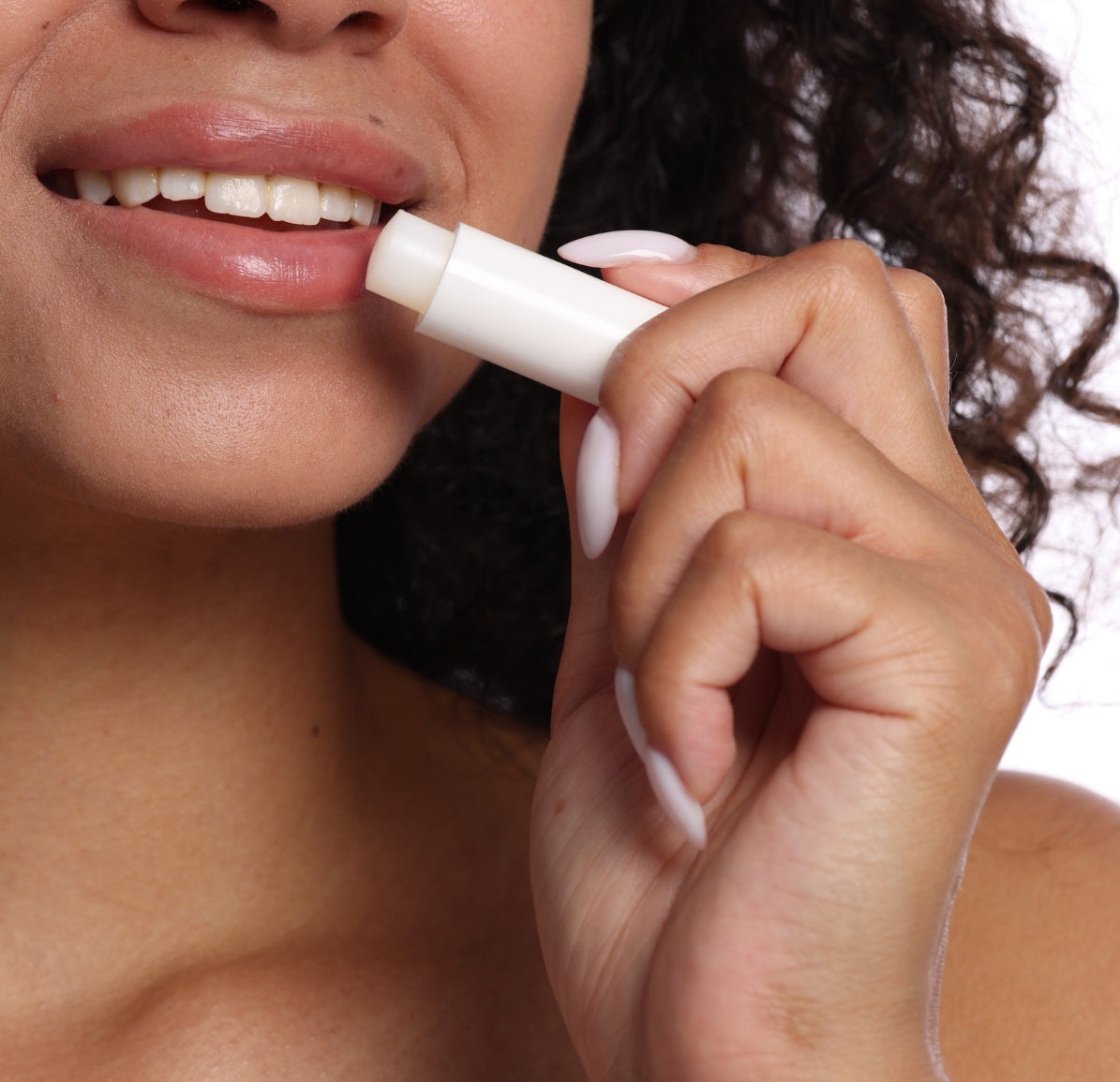 Close-up of a person applying lip balm  to their lips with their hand holding the tube.